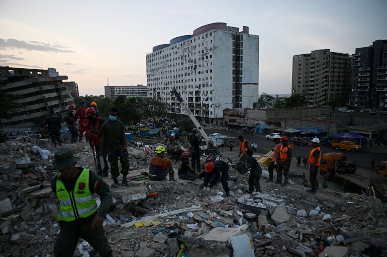 Rescue teams and volunteers search for bodies amid the rubble of a collapsed building in Caraballeda, Venezuela, on July 24, 2026, one month after an earthquake struck the area.