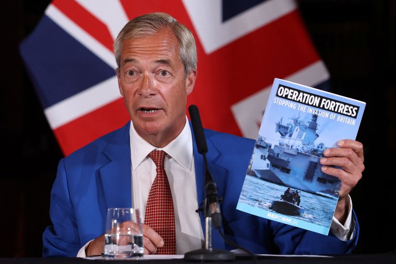 Britain's Reform UK party leader Nigel Farage holds a booklet that reads "Operation Fortress, Stopping the Invasion of Britain" as he speaks.